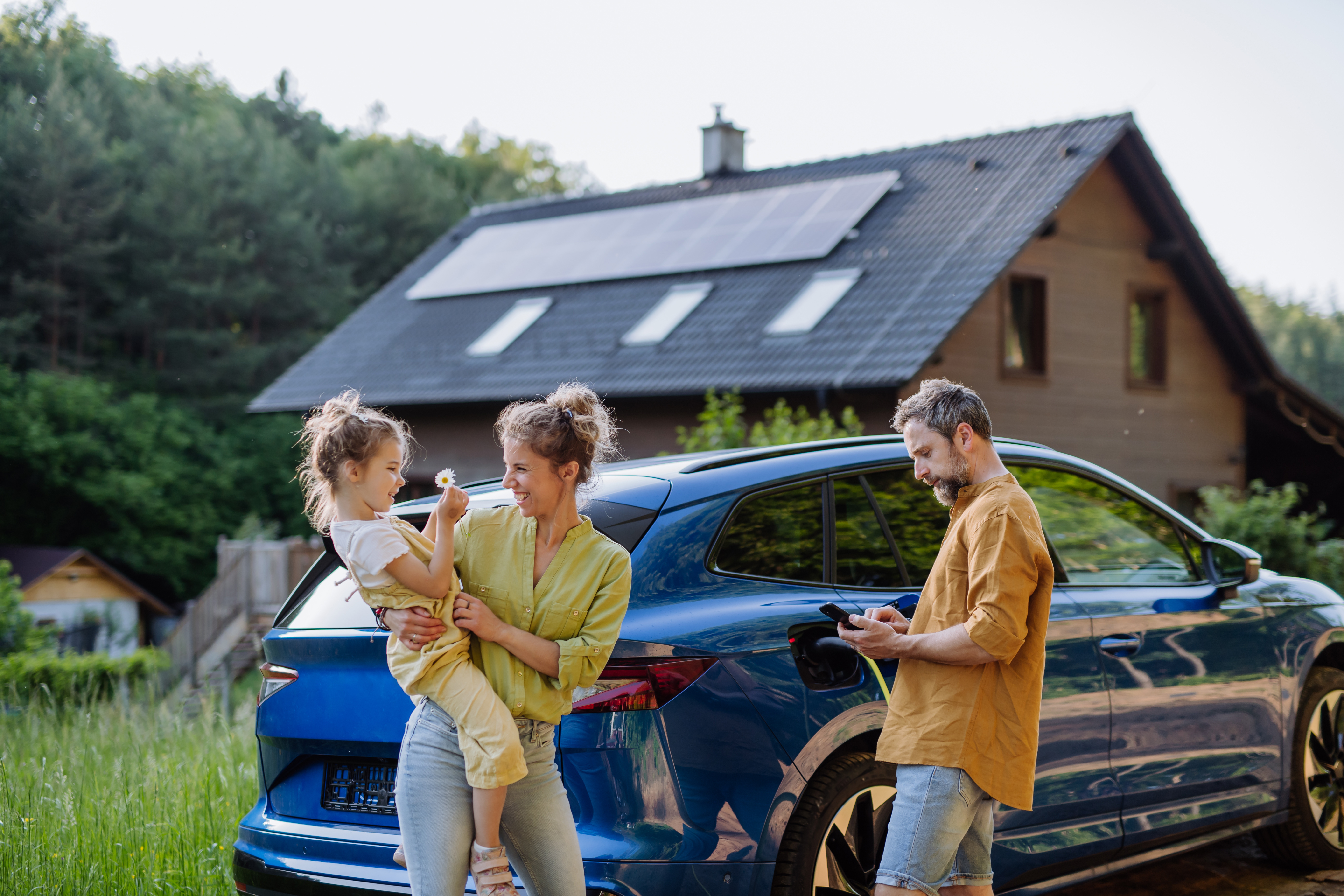 Family with hybrid car and solar panel house